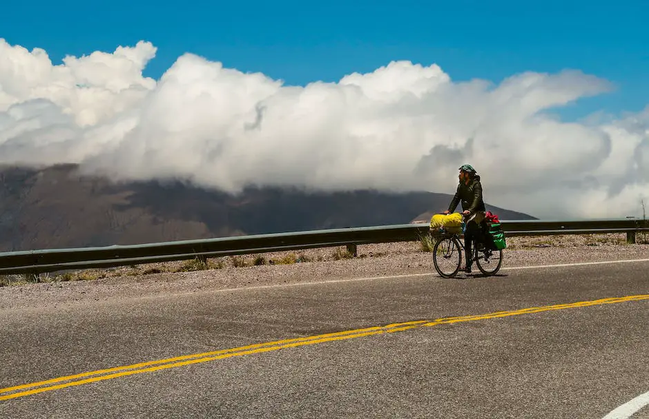 An image of a cyclist riding on a scenic bike path with mountains in the background. The cyclist is wearing a helmet and has a relaxed posture, with bent elbows and a loose grip on the handlebars.