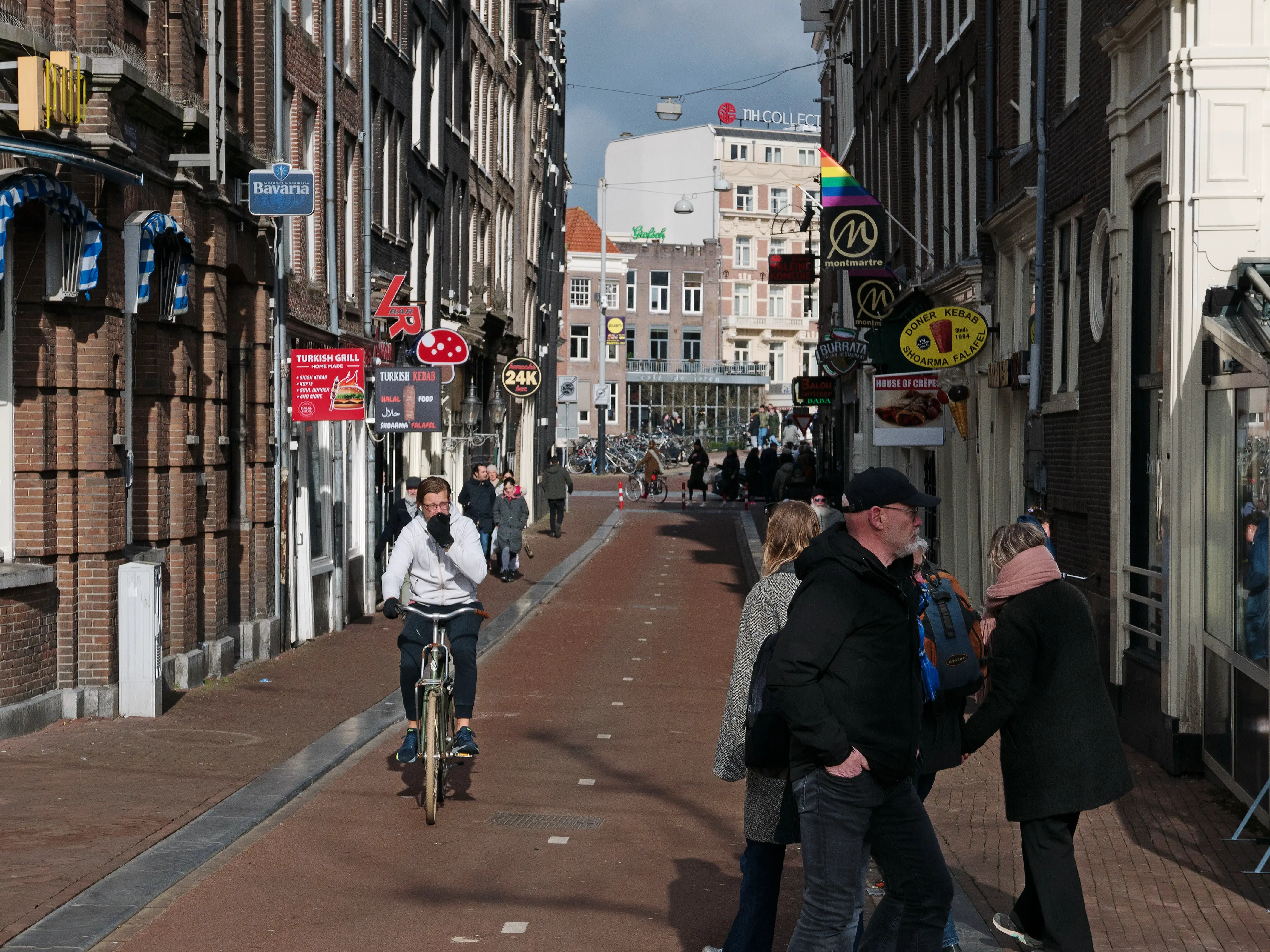 A person riding a bicycle with a helmet on while passing by a car on a city street.
